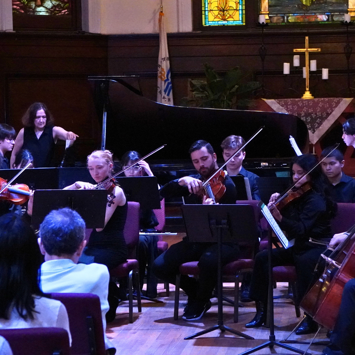 an orchestra playing a classical piece of music, including violins, woodwinds, cello, piano, and percussion