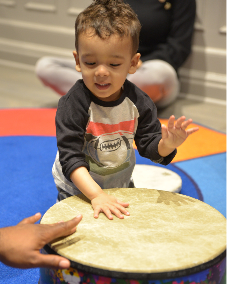 a baby playing a big drum, early childhood music class upper west side