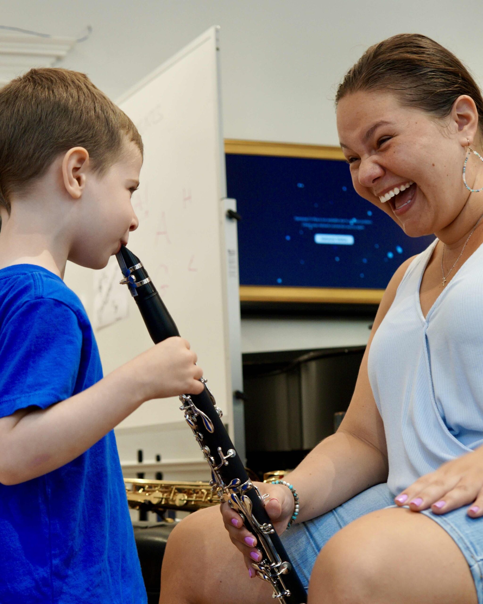 A young boy tries the clarinet for the first time as a Bloomingdale faculty member laughs with delight beside him